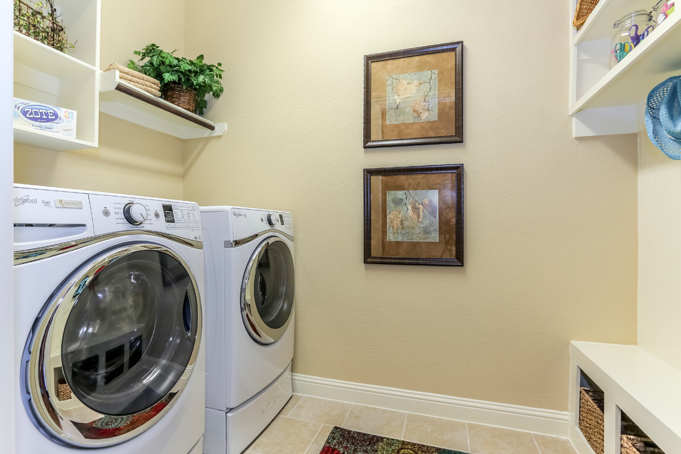 This is an example of a medium sized separated utility room in Houston with open cabinets, white cabinets, beige walls and a side by side washer and dryer.