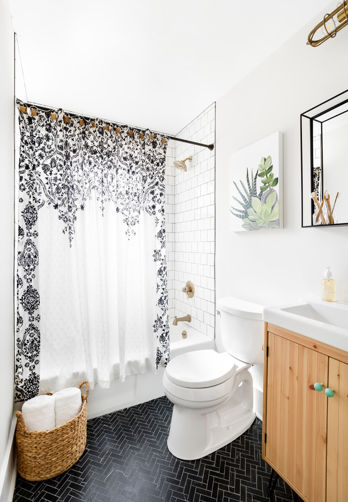 Inspiration for a small beach style bathroom in Charlotte with light wood cabinets, an alcove tub, a shower/bathtub combo, a two-piece toilet, white tile, ceramic tile, marble floors, black floor, a shower curtain, flat-panel cabinets, white walls and a console sink.