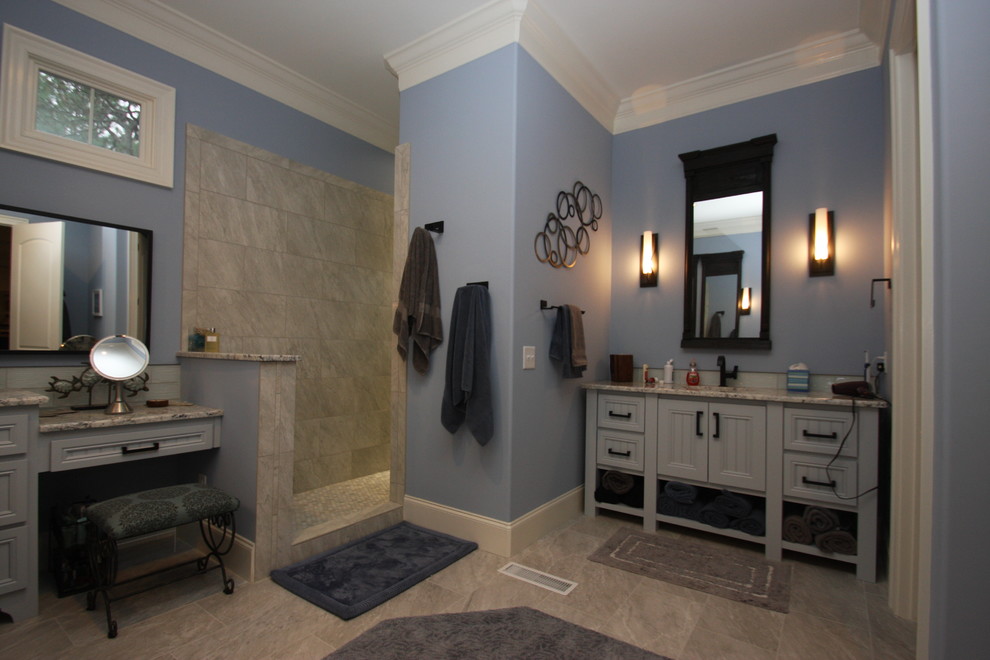 This is an example of a large arts and crafts master bathroom in Raleigh with recessed-panel cabinets, blue cabinets, an alcove shower, a two-piece toilet, beige tile, stone tile, blue walls, porcelain floors, an undermount sink, granite benchtops, beige floor and an open shower.