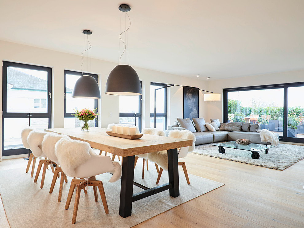 Photo of a contemporary open plan dining in Frankfurt with white walls and light hardwood floors.