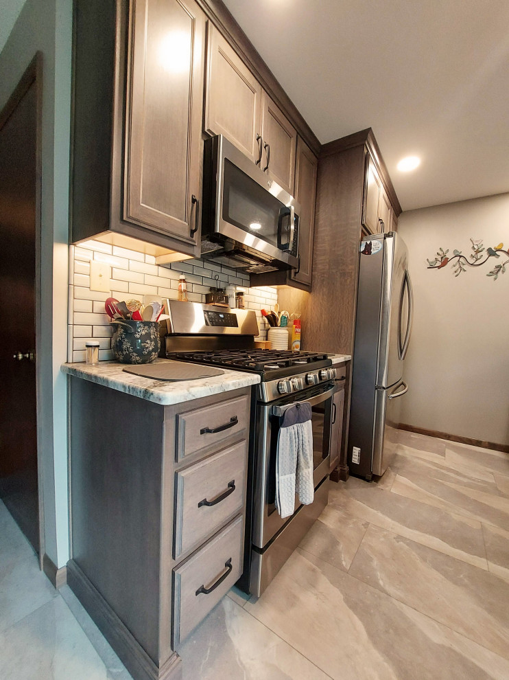 Example of a mid-sized mountain style u-shaped ceramic tile and gray floor eat-in kitchen design in Other with a drop-in sink, dark wood cabinets, granite countertops, white backsplash, subway tile backsplash, stainless steel appliances and beige countertops