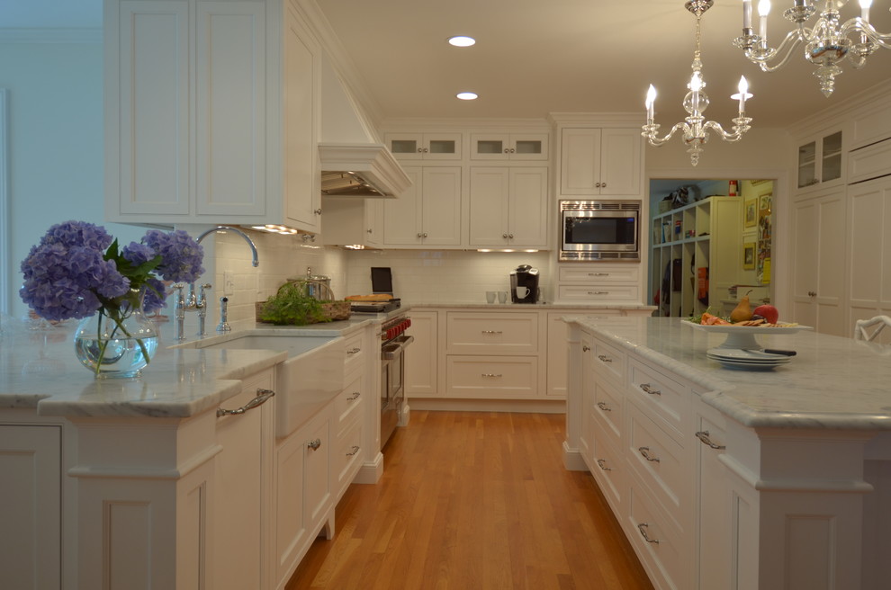 Eat-in kitchen - transitional u-shaped medium tone wood floor eat-in kitchen idea in Boston with a farmhouse sink, beaded inset cabinets, white cabinets, marble countertops, white backsplash, subway tile backsplash, stainless steel appliances and an island