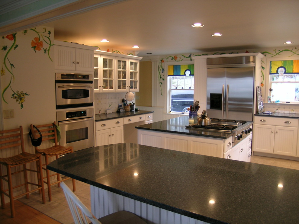Photo of a large country u-shaped eat-in kitchen in Portland Maine with an undermount sink, louvered cabinets, white cabinets, white splashback, porcelain splashback, stainless steel appliances, ceramic floors, with island and granite benchtops.