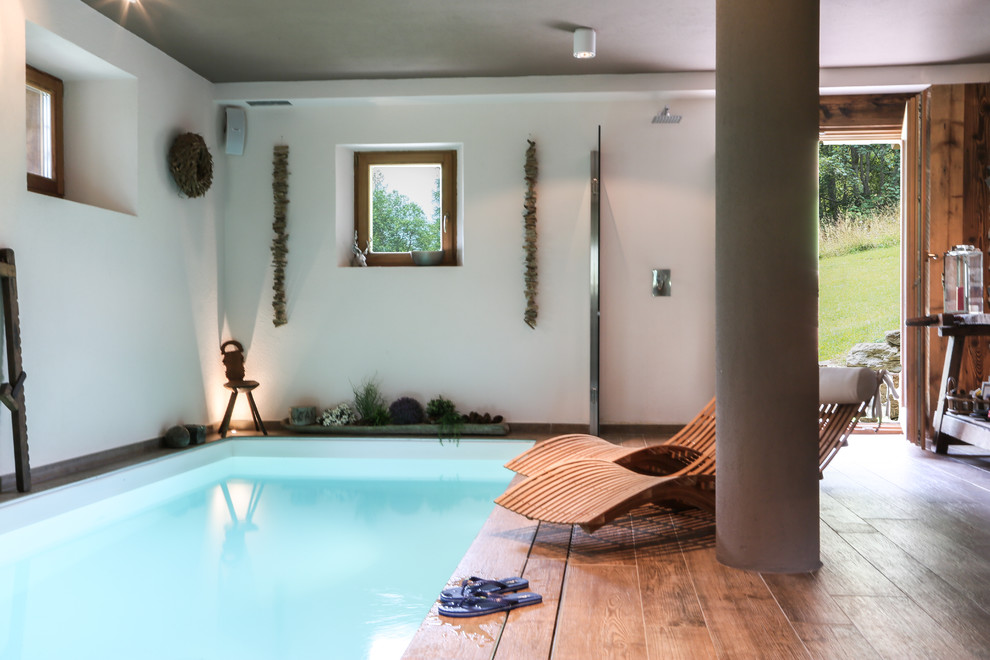 Country indoor rectangular lap pool in Other with a hot tub and decking.