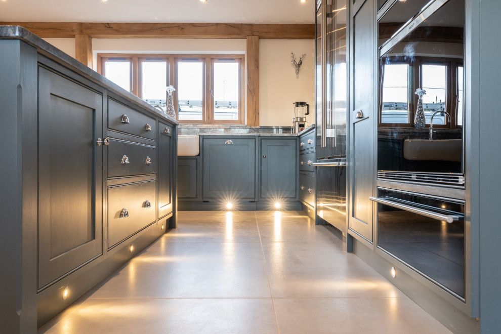 Expansive transitional l-shaped open plan kitchen in Essex with a double-bowl sink, recessed-panel cabinets, grey cabinets, granite benchtops, panelled appliances, travertine floors, with island, beige floor and grey benchtop.