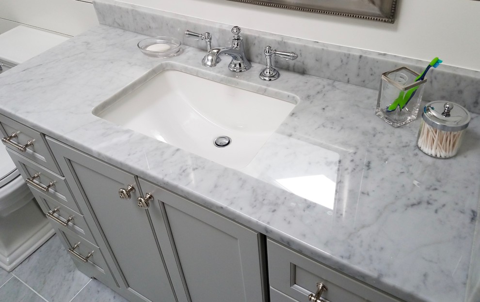 Inspiration for a mid-sized transitional 3/4 bathroom in Bridgeport with recessed-panel cabinets, grey cabinets, an alcove shower, a one-piece toilet, white walls, marble floors, an undermount sink, marble benchtops, grey floor, a hinged shower door, gray tile and subway tile.