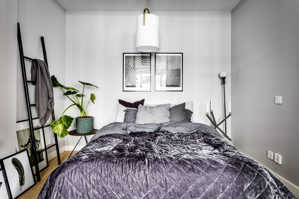 Small scandinavian bedroom in Stockholm with grey walls, light hardwood floors and beige floor.