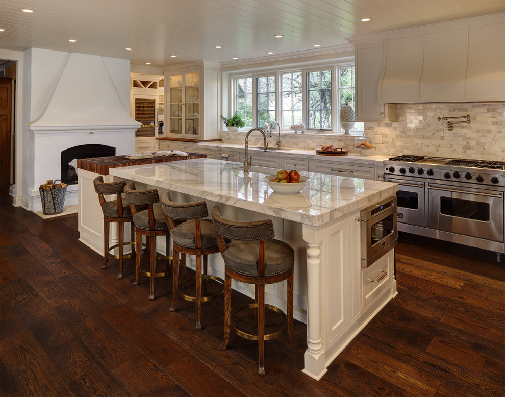 This is an example of a traditional kitchen in Cleveland with a farmhouse sink, shaker cabinets, white cabinets, white splashback, stainless steel appliances, dark hardwood floors and with island.