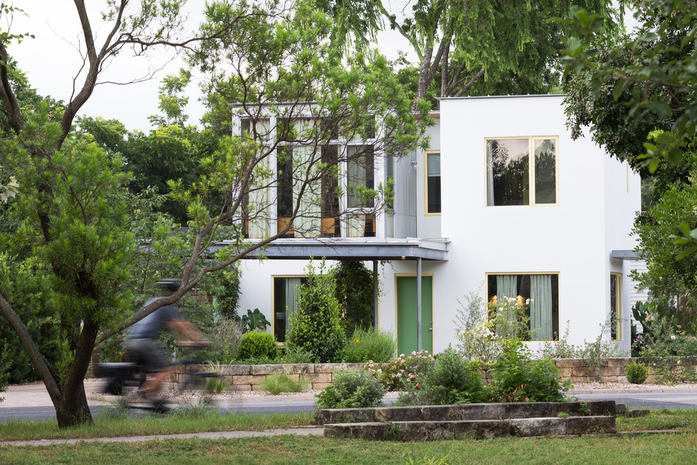 Small eclectic two-storey stucco white house exterior in Austin with a flat roof and a metal roof.