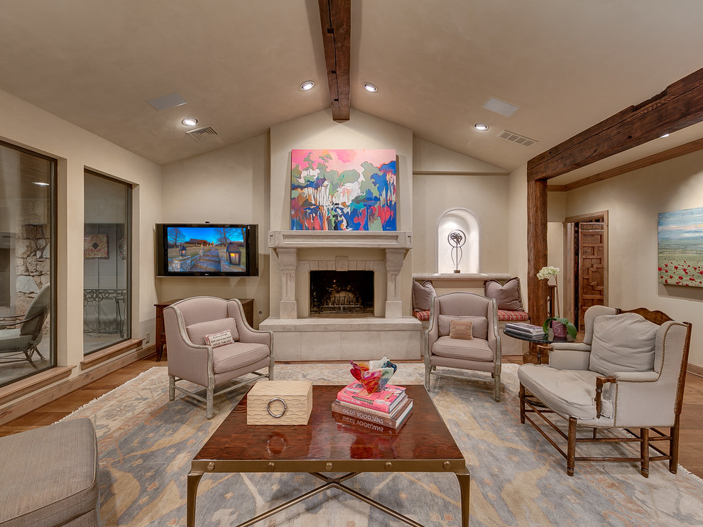 Mediterranean family room in Oklahoma City with beige walls, dark hardwood floors, a standard fireplace, a stone fireplace surround and a wall-mounted tv.