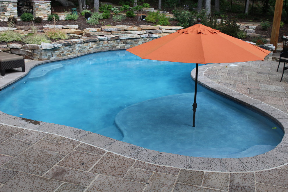 Country backyard custom-shaped natural pool in DC Metro with natural stone pavers.
