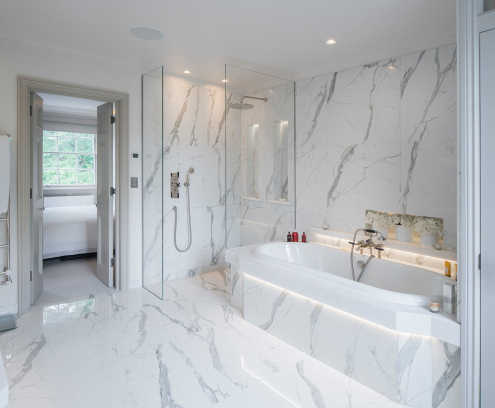 Inspiration for a transitional wet room bathroom in London with a drop-in tub, marble, marble floors and an open shower.