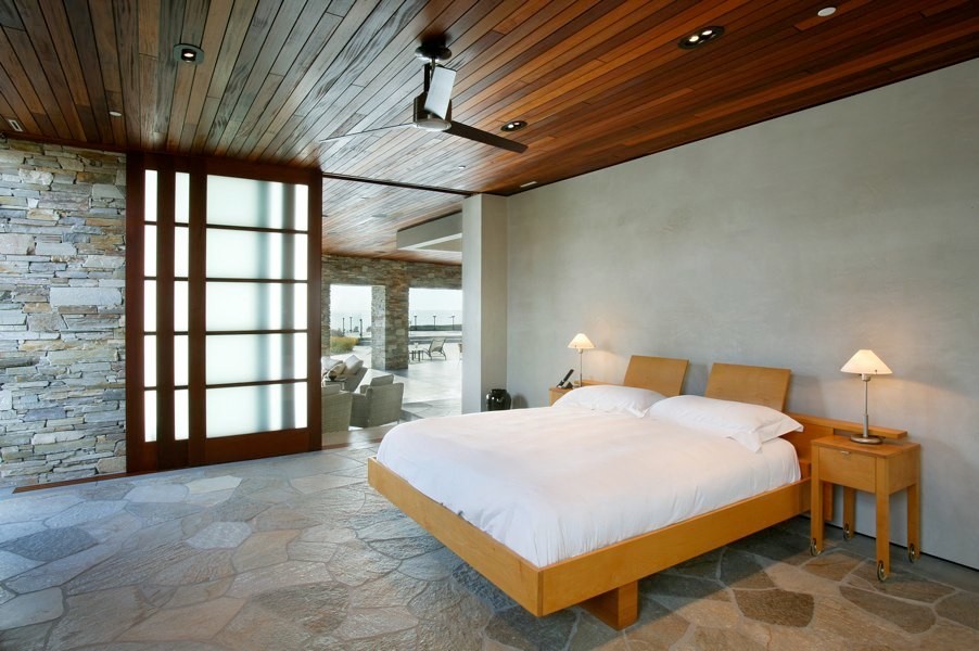 This is an example of a large contemporary master bedroom in Orange County with beige walls, no fireplace and grey floor.