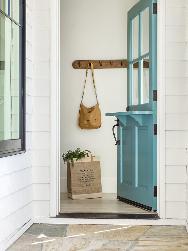 Photo of a beach style front door in Orange County with white walls, light hardwood floors, a dutch front door, a blue front door and beige floor.