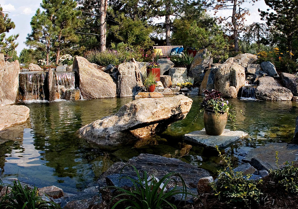 This is an example of a mid-sized rustic partial sun backyard stone water fountain landscape in Denver for spring.