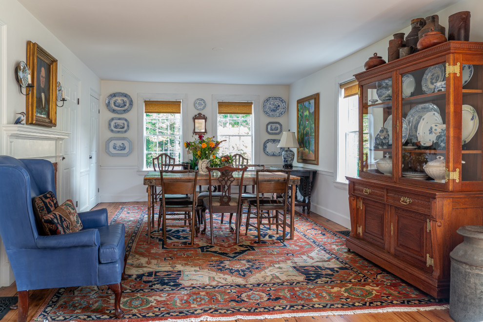 This is an example of a country dining room in Boston with light hardwood floors, a standard fireplace and a wood fireplace surround.