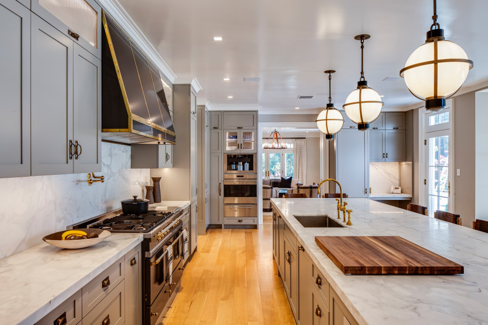 This is an example of a large classic u-shaped kitchen/diner in New York with a submerged sink, shaker cabinets, grey cabinets, marble worktops, white splashback, marble splashback, black appliances, light hardwood flooring, an island, beige floors and white worktops.