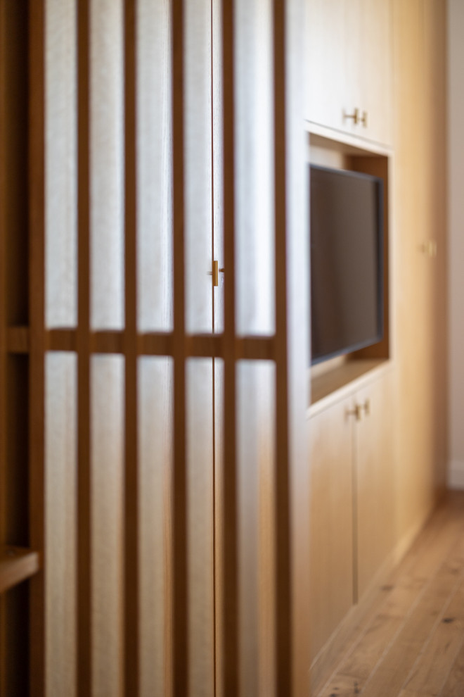 Modelo de armario unisex tradicional renovado de tamaño medio con armarios con rebordes decorativos, puertas de armario de madera clara, suelo de madera oscura y suelo marrón