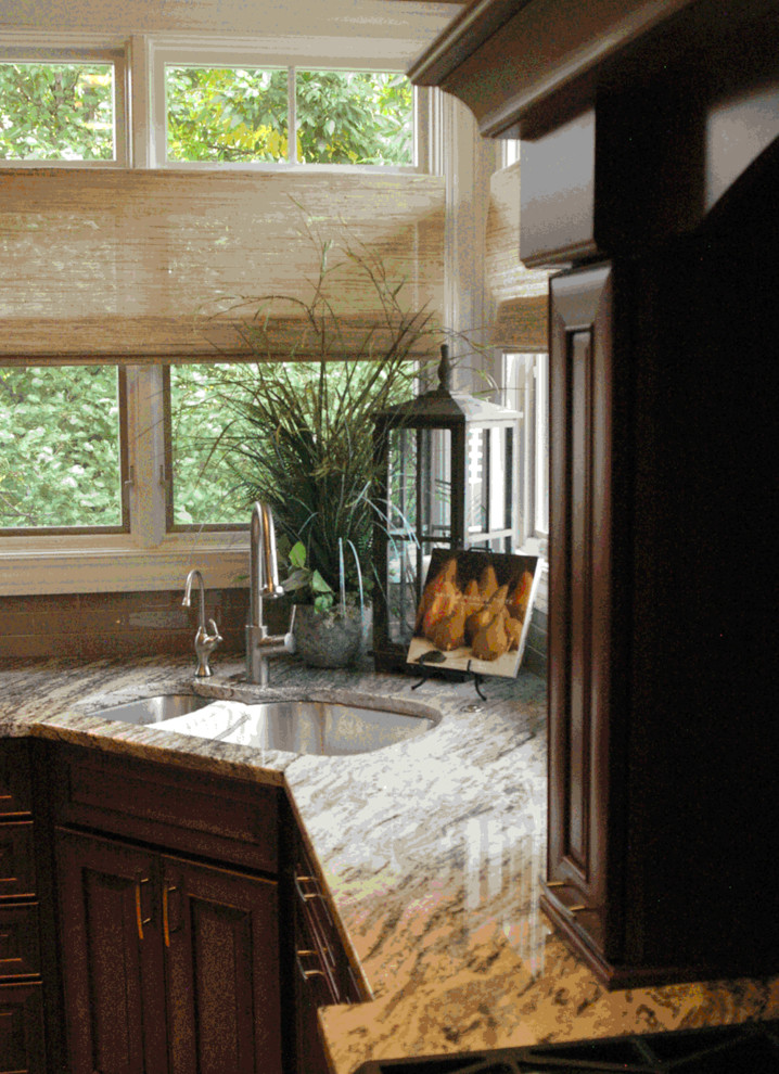 Inspiration for a mid-sized transitional l-shaped kitchen remodel with a double-bowl sink, raised-panel cabinets, dark wood cabinets, granite countertops, gray backsplash, glass tile backsplash, stainless steel appliances and an island