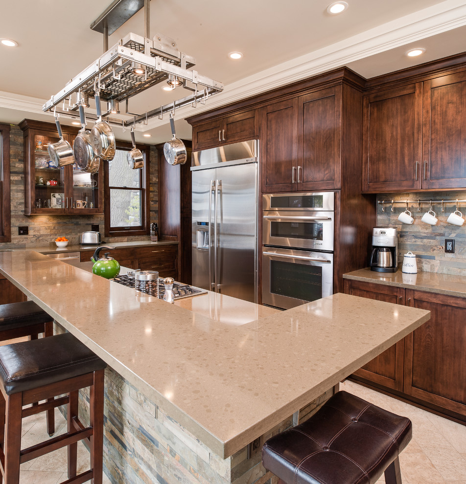 Inspiration for a mid-sized transitional l-shaped travertine floor eat-in kitchen remodel with an undermount sink, recessed-panel cabinets, dark wood cabinets, quartz countertops, multicolored backsplash, stone slab backsplash, stainless steel appliances and an island