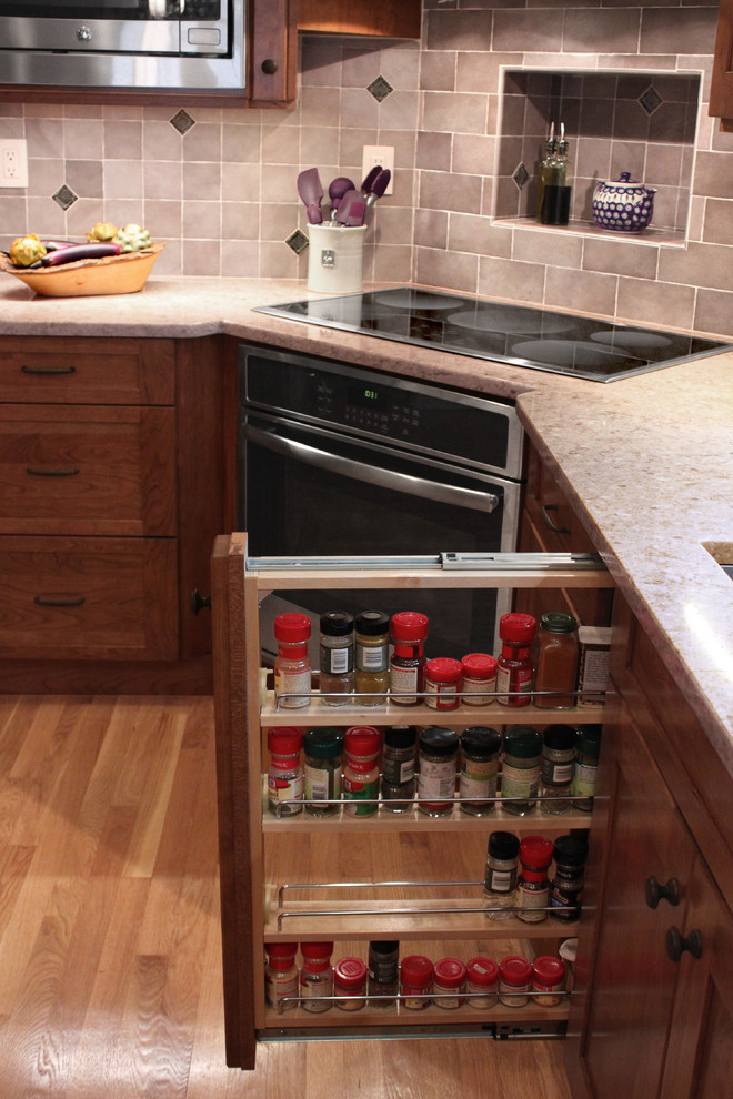 Inspiration for a large transitional u-shaped light wood floor eat-in kitchen remodel in Boston with an undermount sink, shaker cabinets, medium tone wood cabinets, quartz countertops, gray backsplash, porcelain backsplash, stainless steel appliances and a peninsula
