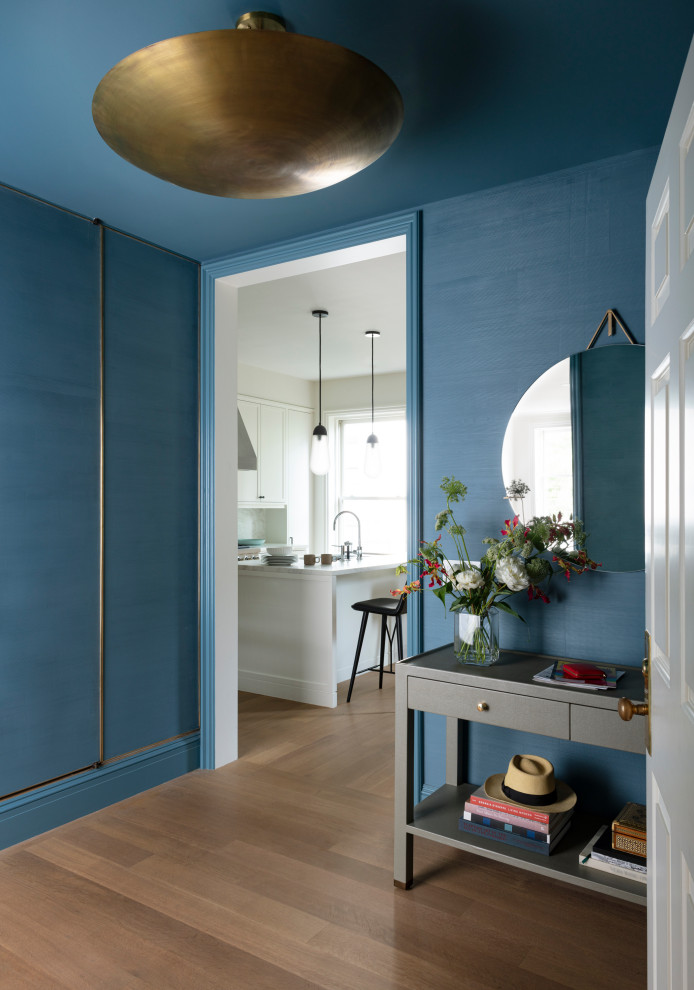 Inspiration för mellanstora klassiska foajéer, med blå väggar, ljust trägolv, en enkeldörr och en vit dörr