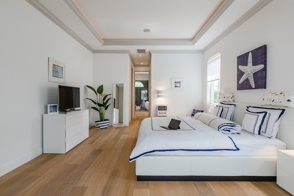 Contemporary bedroom in Miami with white walls, medium hardwood floors and brown floor.