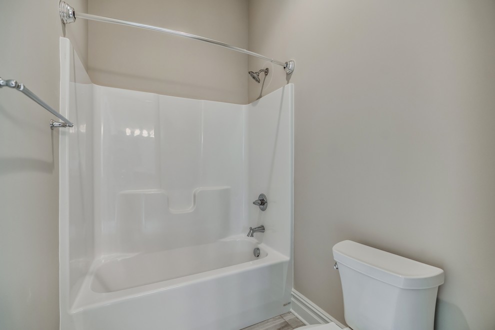Tub/shower combo - transitional kids' brown tile and ceramic tile ceramic tile and brown floor tub/shower combo idea with raised-panel cabinets, medium tone wood cabinets, a two-piece toilet, gray walls, an undermount sink, granite countertops and brown countertops
