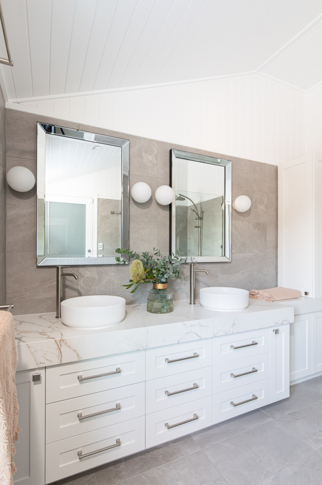 Inspiration for a transitional master bathroom in Brisbane with shaker cabinets, white cabinets, a one-piece toilet, gray tile, travertine, white walls, travertine floors, a vessel sink, marble benchtops, grey floor, a hinged shower door, white benchtops, a double vanity, a built-in vanity, vaulted and panelled walls.