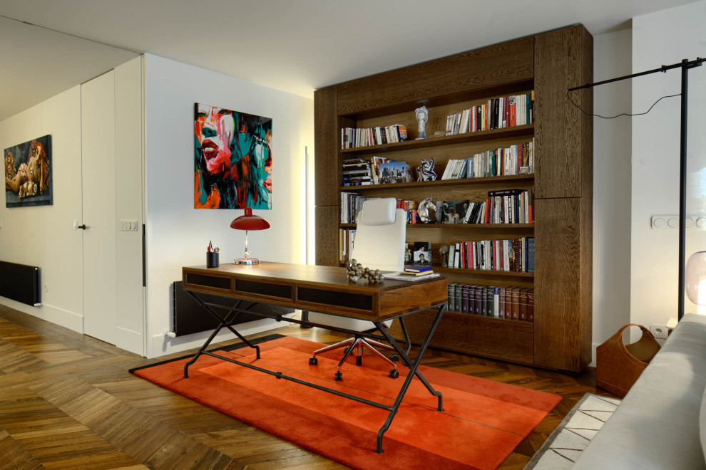 This is an example of a mid-sized contemporary study room in Other with red walls, dark hardwood floors, no fireplace, a freestanding desk and brown floor.