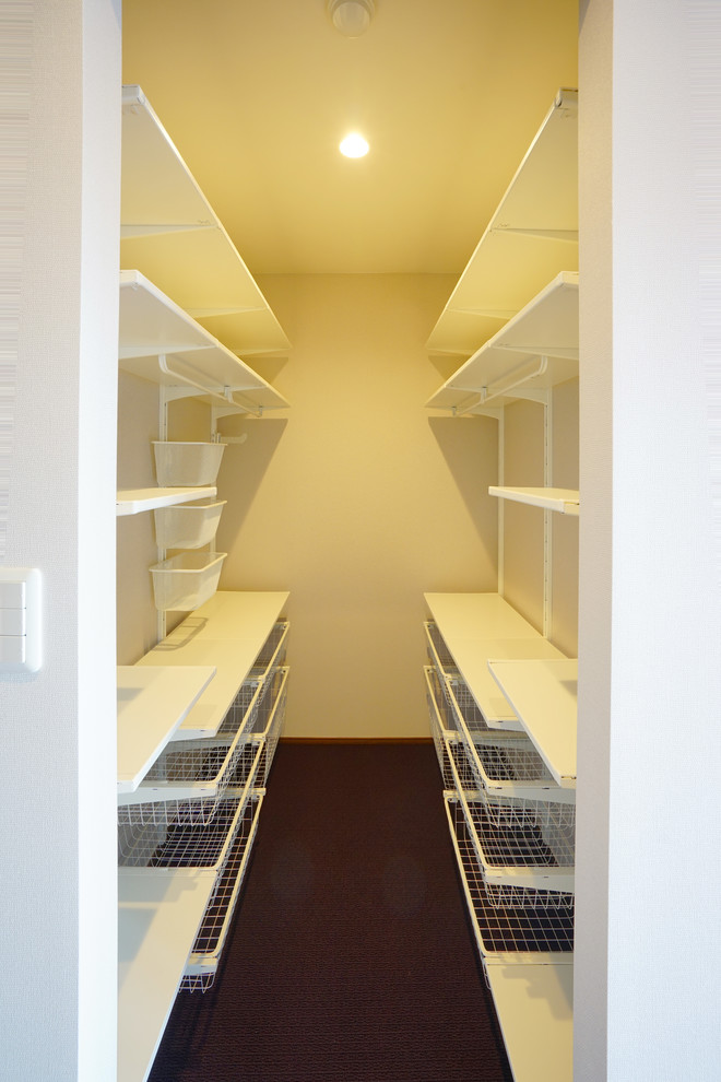 Photo of a mid-sized modern gender-neutral walk-in wardrobe in Other with carpet, purple floor, open cabinets and wallpaper.