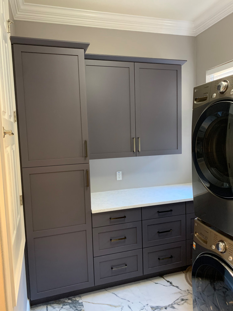 Large contemporary galley dedicated laundry room in Orlando with an undermount sink, recessed-panel cabinets, grey cabinets, quartz benchtops, white splashback, engineered quartz splashback, grey walls, porcelain floors, a stacked washer and dryer, white floor and white benchtop.
