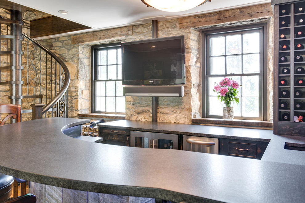 Photo of a large country l-shaped seated home bar in DC Metro with a drop-in sink, beaded inset cabinets, distressed cabinets, granite benchtops and medium hardwood floors.
