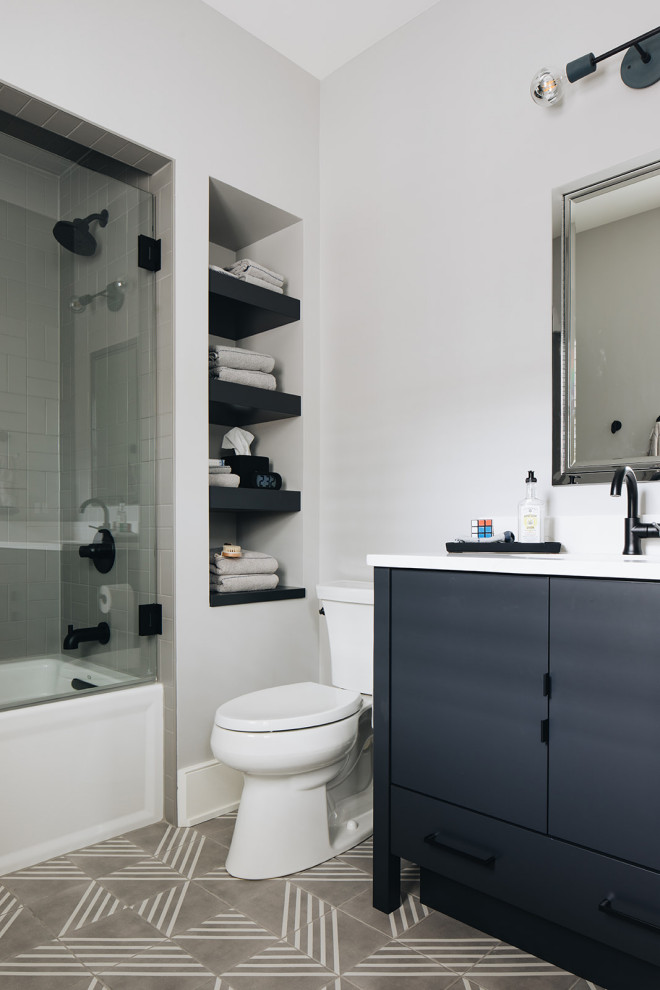 Inspiration for a large transitional kids bathroom in Chicago with furniture-like cabinets, blue cabinets, a drop-in tub, an alcove shower, a two-piece toilet, gray tile, ceramic tile, grey walls, dark hardwood floors, an undermount sink, engineered quartz benchtops, grey floor, a hinged shower door and white benchtops.