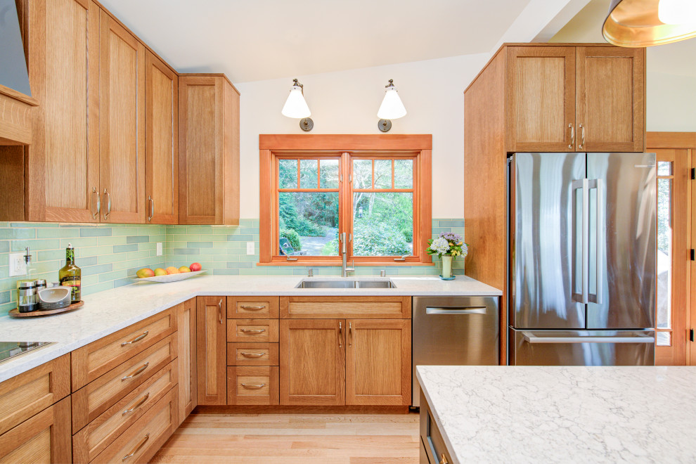 Example of a mid-sized transitional u-shaped medium tone wood floor, brown floor and vaulted ceiling eat-in kitchen design in Seattle with a double-bowl sink, recessed-panel cabinets, light wood cabinets, quartz countertops, blue backsplash, ceramic backsplash, stainless steel appliances, an island and white countertops