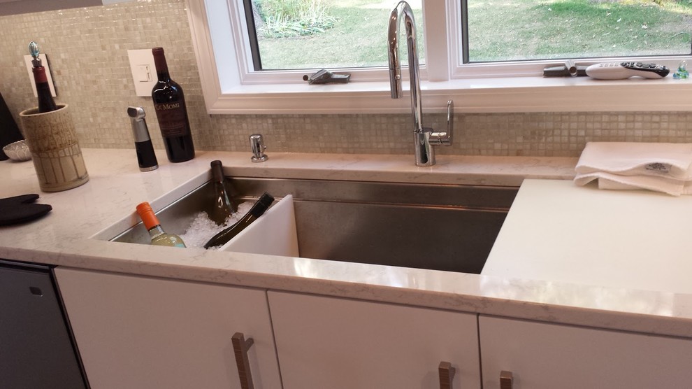 Inspiration for a small transitional galley medium tone wood floor enclosed kitchen remodel with an undermount sink, flat-panel cabinets, white cabinets, quartz countertops, white backsplash, mosaic tile backsplash, stainless steel appliances and a peninsula