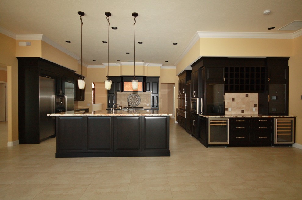 Open concept kitchen - huge transitional u-shaped porcelain tile open concept kitchen idea in Tampa with raised-panel cabinets, black cabinets, beige backsplash, stainless steel appliances and an island
