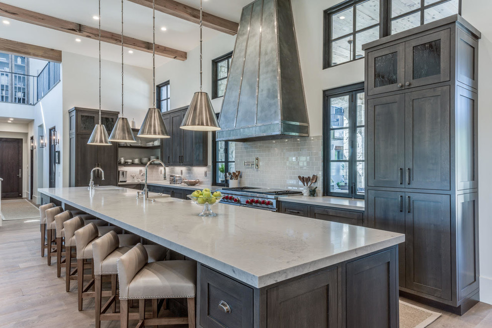 Country l-shaped kitchen in Sacramento with a farmhouse sink, shaker cabinets, grey cabinets, grey splashback, subway tile splashback, panelled appliances, light hardwood floors, with island, brown floor and grey benchtop.