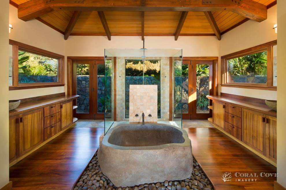 This is an example of a large tropical master bathroom in Hawaii with medium wood cabinets, wood benchtops, a freestanding tub, an open shower, beige walls and light hardwood floors.