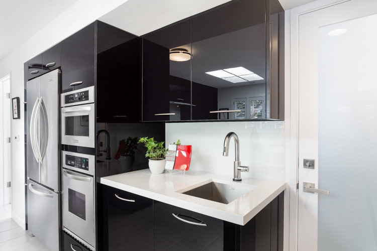 Photo of a contemporary u-shaped kitchen in San Francisco with an undermount sink, flat-panel cabinets, black cabinets, white splashback, glass sheet splashback, stainless steel appliances and a peninsula.