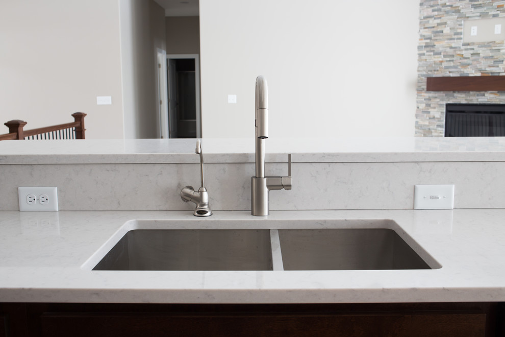 Enclosed kitchen - mid-sized transitional l-shaped dark wood floor enclosed kitchen idea with a double-bowl sink, shaker cabinets, dark wood cabinets, quartz countertops, gray backsplash, stone tile backsplash, stainless steel appliances and an island