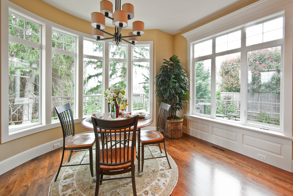 Traditional dining room in Seattle with yellow walls and dark hardwood floors.