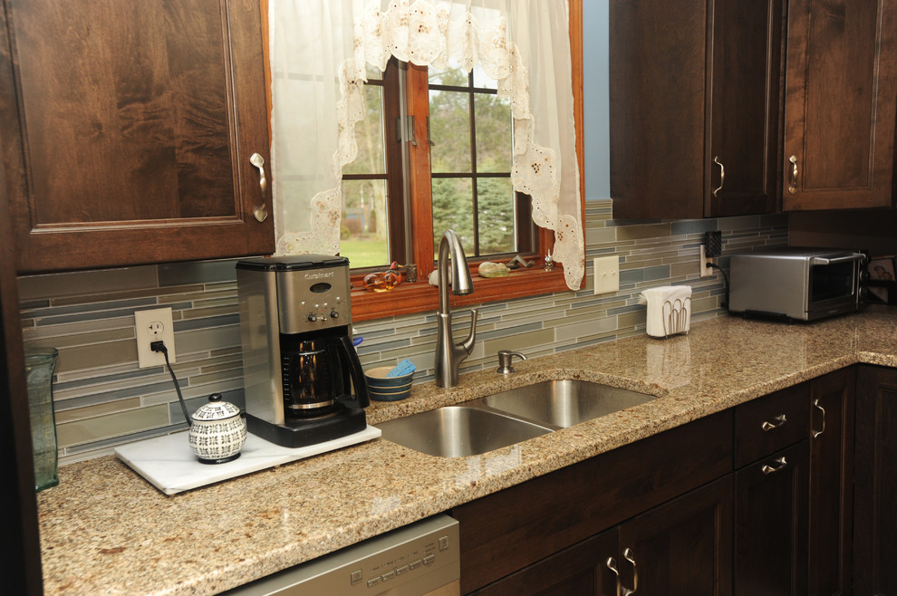 Mid-sized transitional l-shaped ceramic tile eat-in kitchen photo with an undermount sink, recessed-panel cabinets, dark wood cabinets, granite countertops, multicolored backsplash, glass tile backsplash, stainless steel appliances and an island