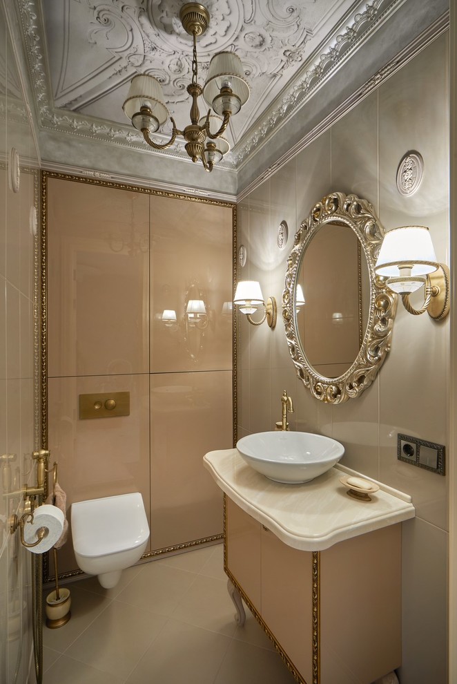Photo of a traditional powder room in Other with flat-panel cabinets, beige cabinets, a wall-mount toilet, beige tile, a vessel sink and beige floor.