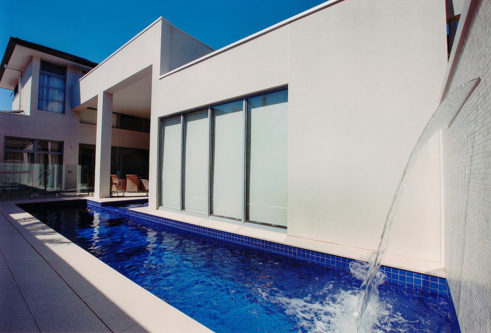 This is an example of a mid-sized modern backyard rectangular lap pool in Adelaide with a water feature and tile.