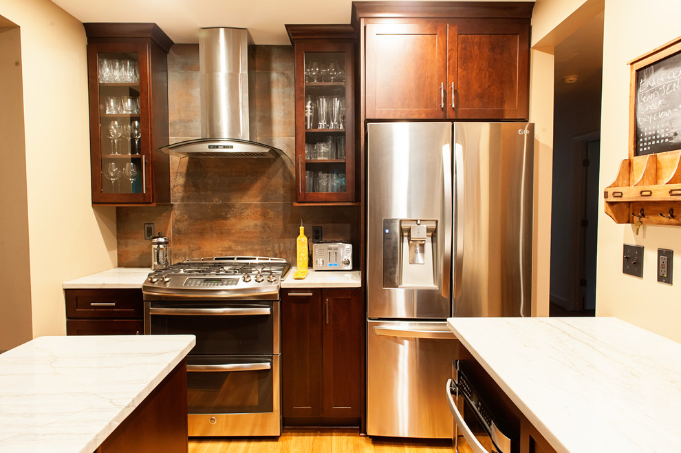 Mid-sized transitional galley light wood floor eat-in kitchen photo in DC Metro with a farmhouse sink, shaker cabinets, dark wood cabinets, quartzite countertops, metallic backsplash, porcelain backsplash, stainless steel appliances and an island