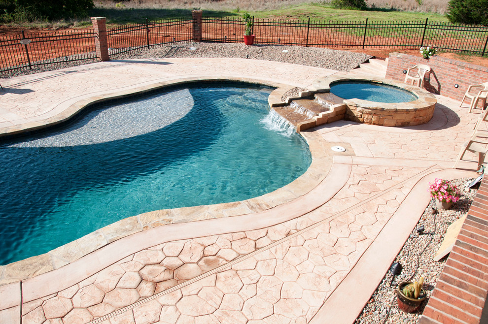 This is an example of a tropical backyard custom-shaped natural pool in Oklahoma City.