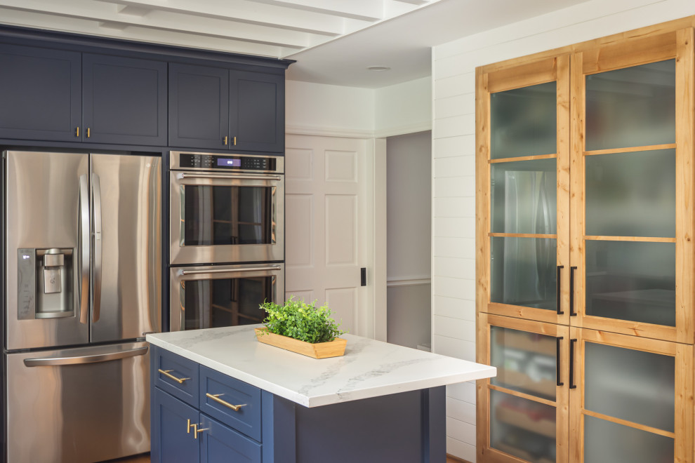 Mid-sized transitional u-shaped medium tone wood floor and brown floor open concept kitchen photo in Raleigh with an undermount sink, recessed-panel cabinets, blue cabinets, quartzite countertops, white backsplash, subway tile backsplash, stainless steel appliances, an island and white countertops