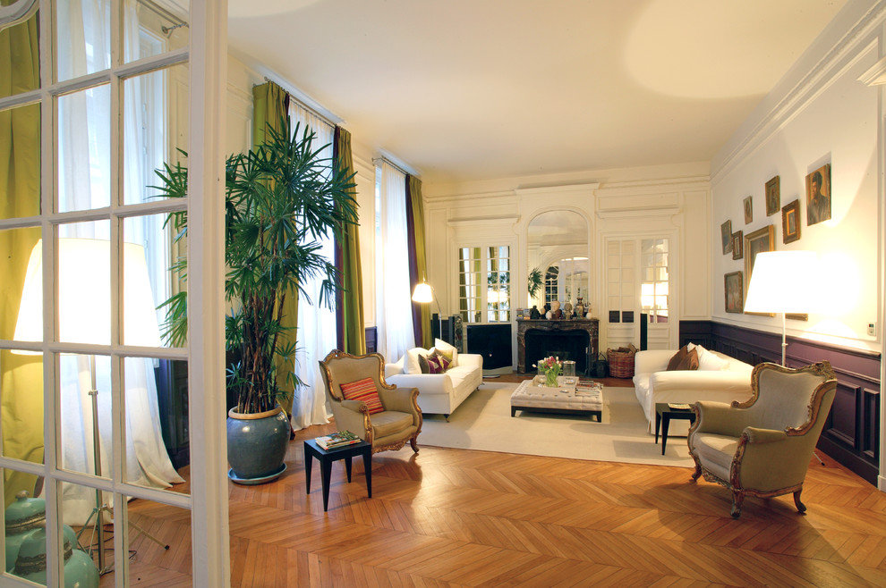Photo of an expansive traditional formal enclosed living room in Paris with multi-coloured walls, medium hardwood floors, a standard fireplace, a stone fireplace surround and no tv.