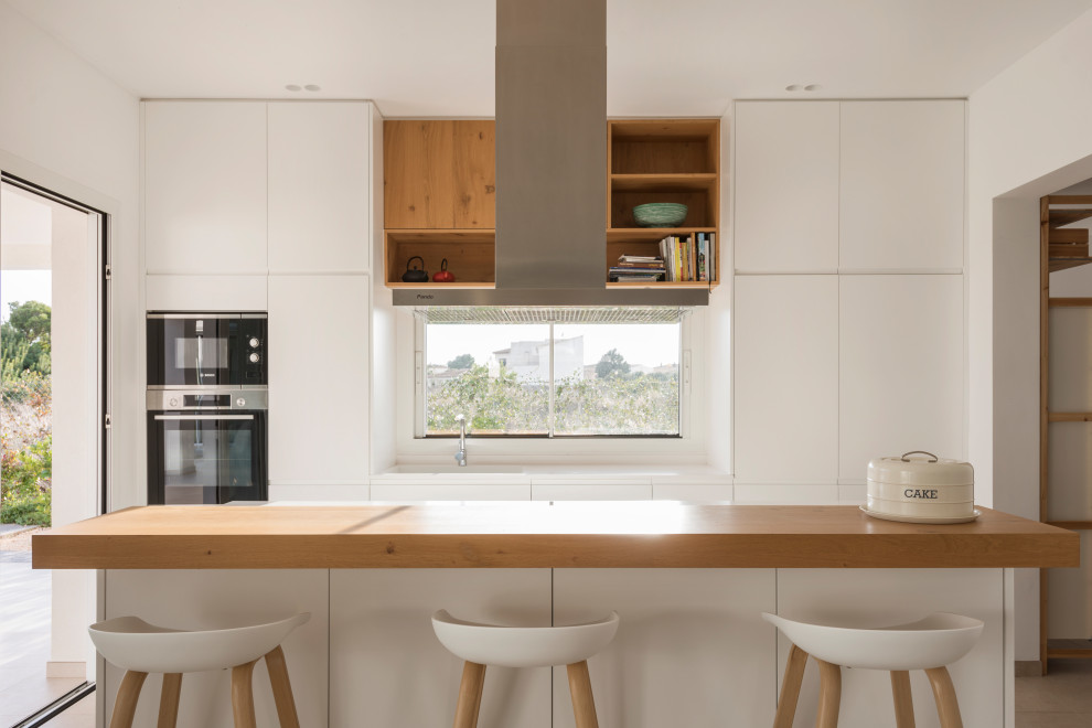 Moderne Küche mit flächenbündigen Schrankfronten, weißen Schränken, Arbeitsplatte aus Holz und Kücheninsel in Palma de Mallorca